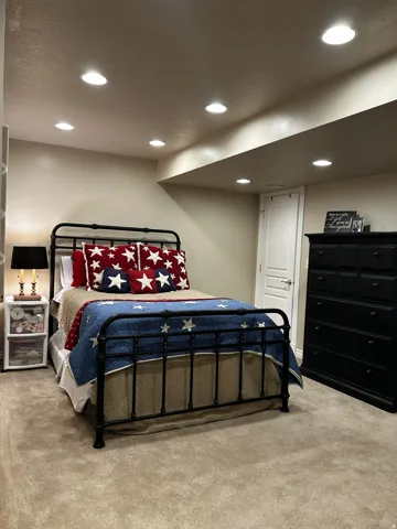 Carpeted room with recessed lighting and a painted door