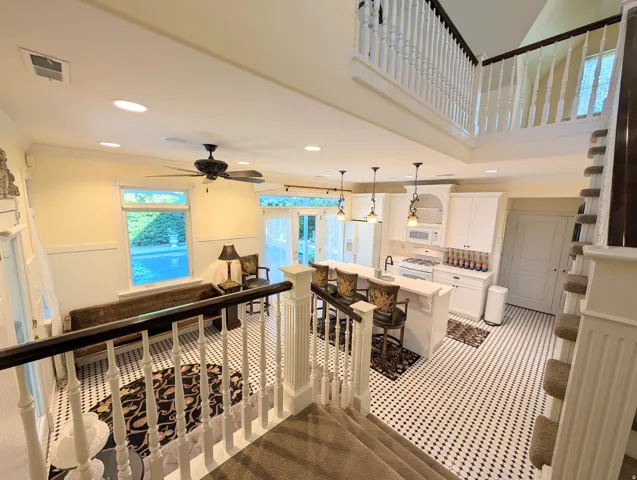 Open-concept main level featuring a kitchen with white cabinetry and a central island with pendant lighting