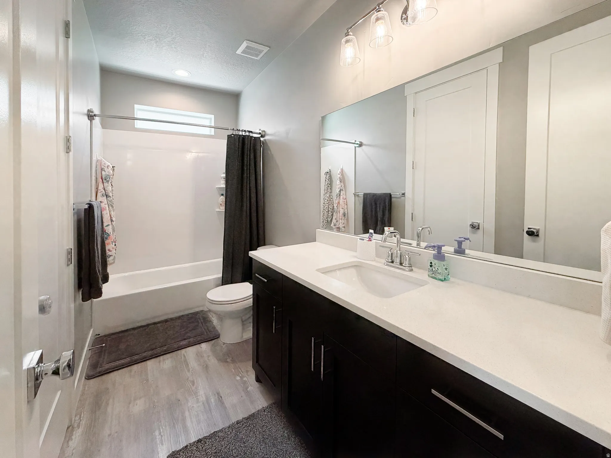 Bathroom featuring a dark wood-finish vanity with a light-colored countertop, an integrated sink, and a large mirror
