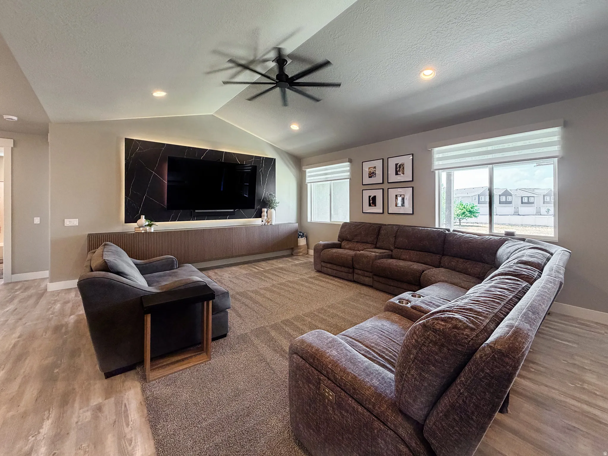 Spacious living area featuring a vaulted ceiling with a modern ceiling fan, recessed lighting, and wood-finish flooring