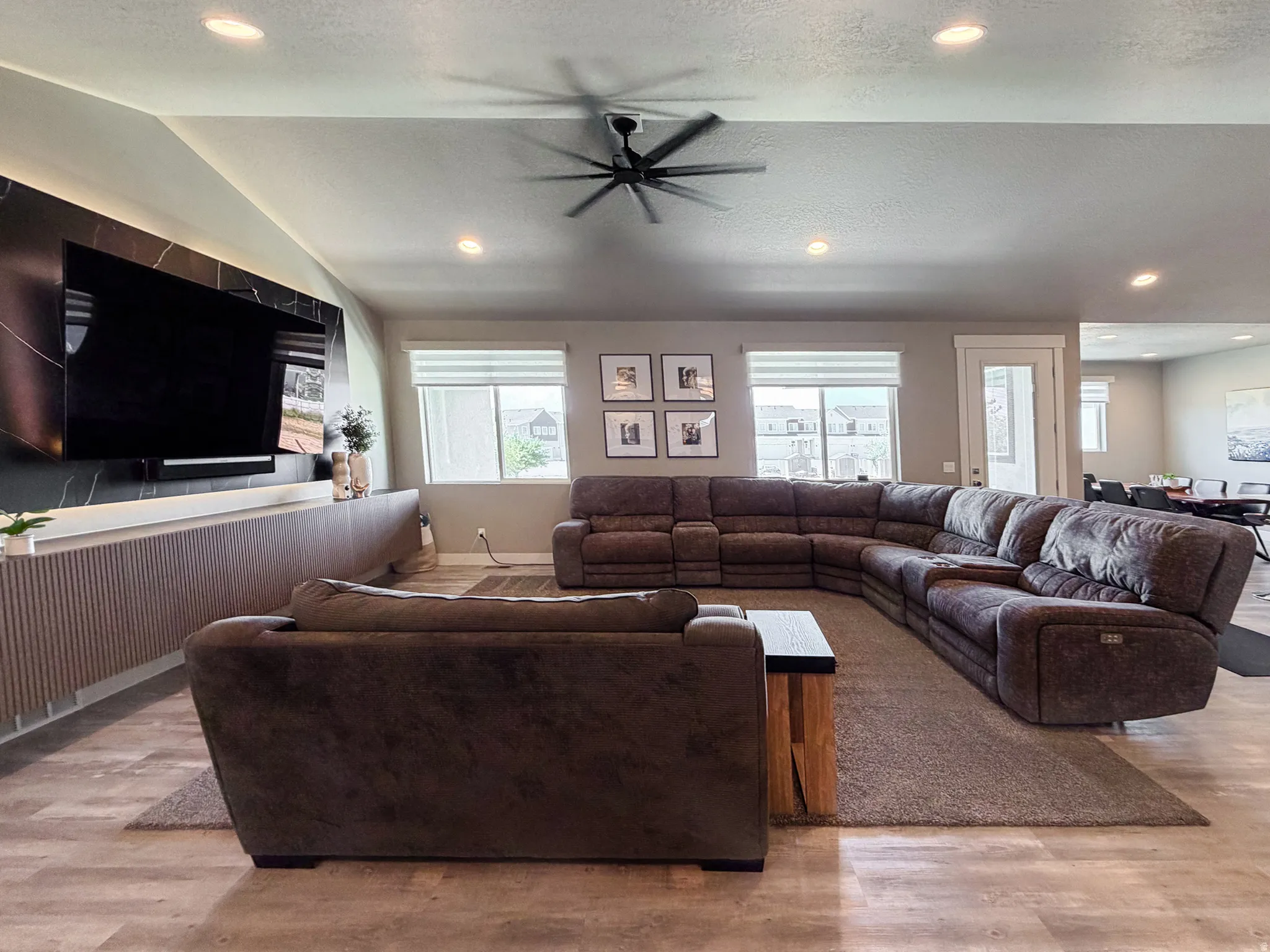Spacious living area featuring LVT flooring, recessed lighting, and a contemporary ceiling fan