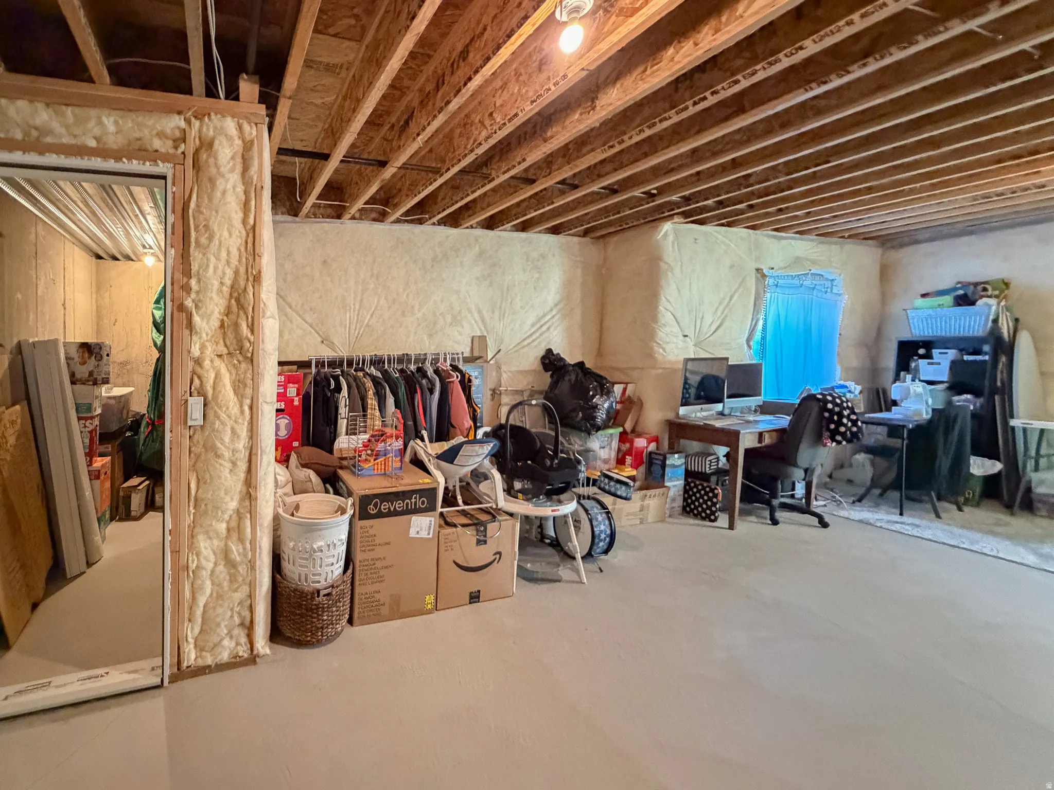 Unfinished basement featuring exposed wood ceiling joists and wall insulation
