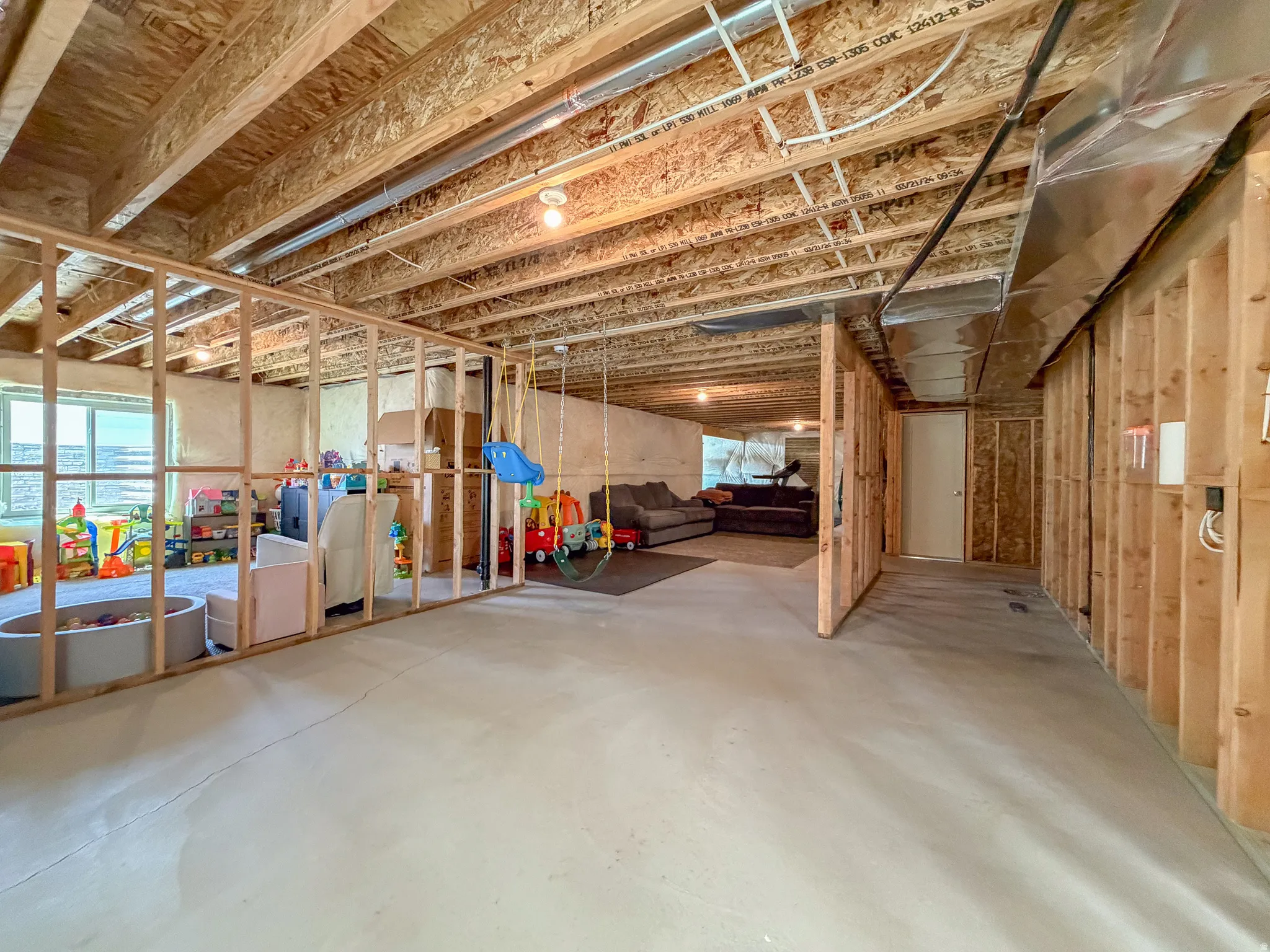Unfinished lower level with wood framing, exposed ceiling joists, and concrete flooring