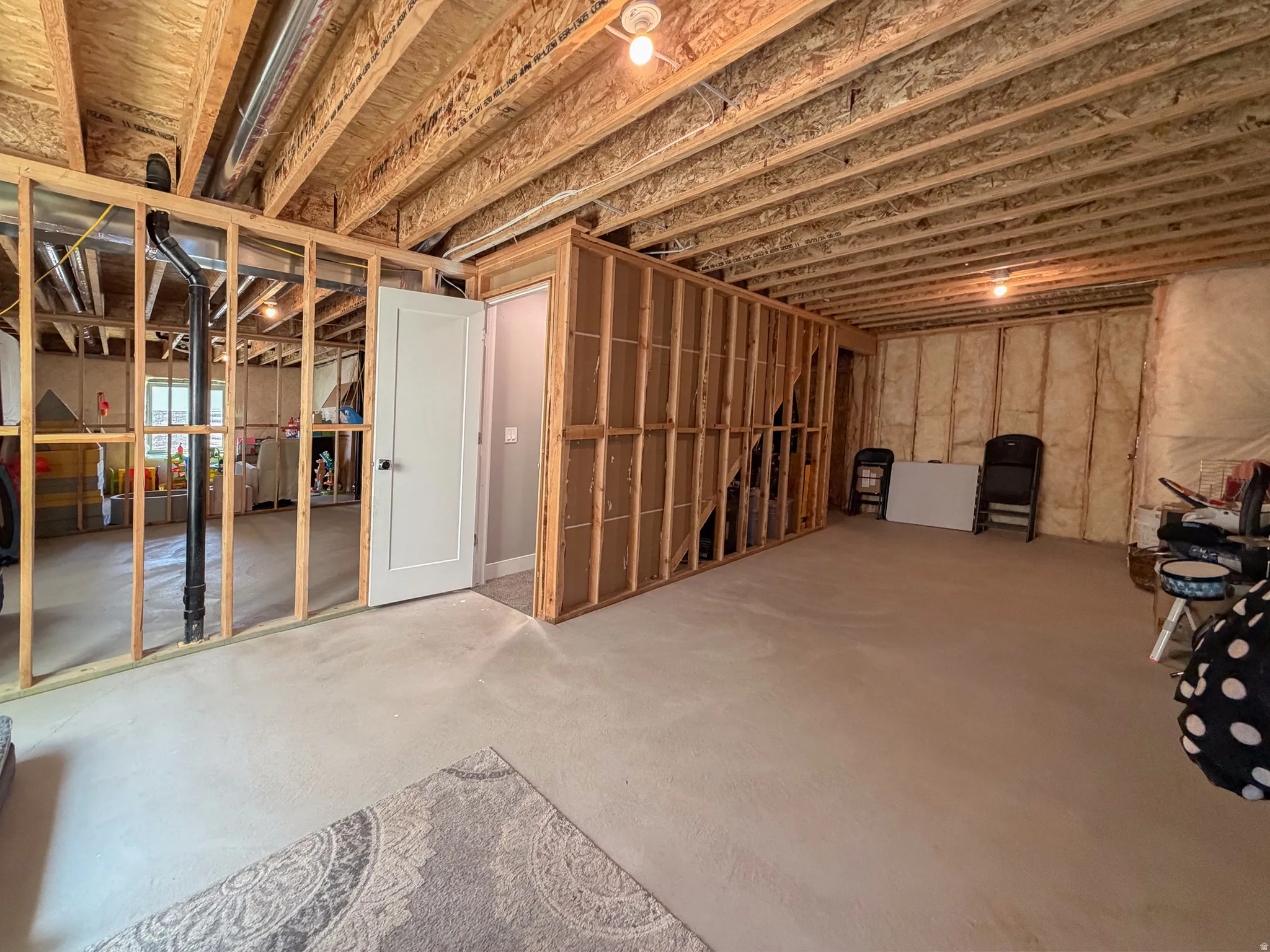 Unfinished basement offering exposed wood framing, an existing interior door, and visible ductwork