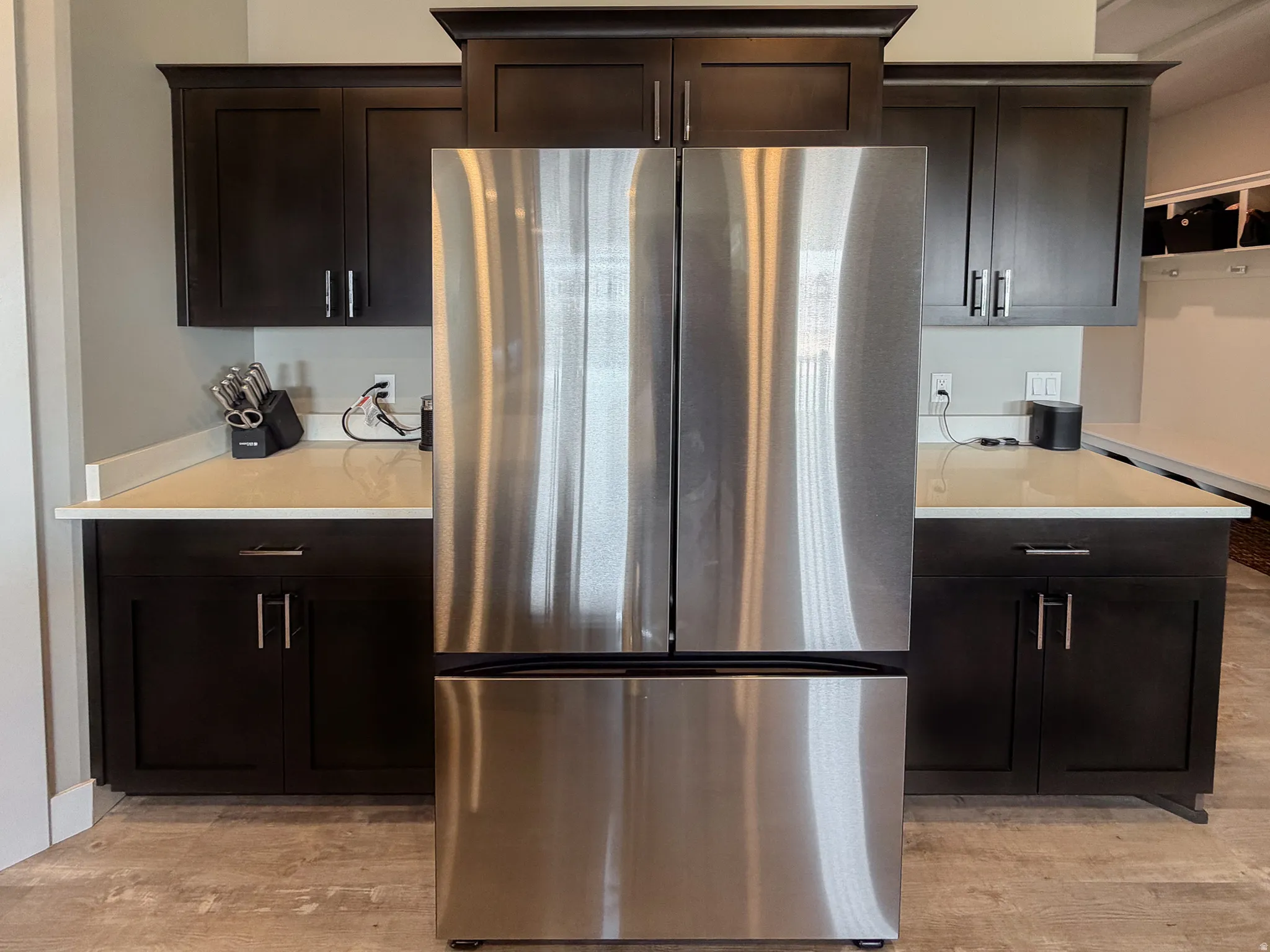 Stainless steel French door refrigerator flanked by dark wood cabinetry