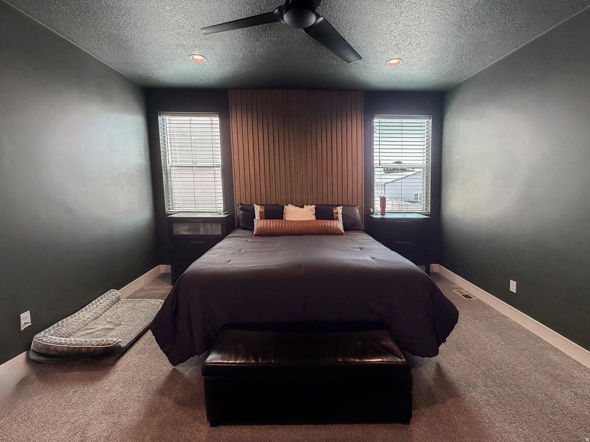 Bedroom featuring dark wall paint and a textured wood-panel accent wall