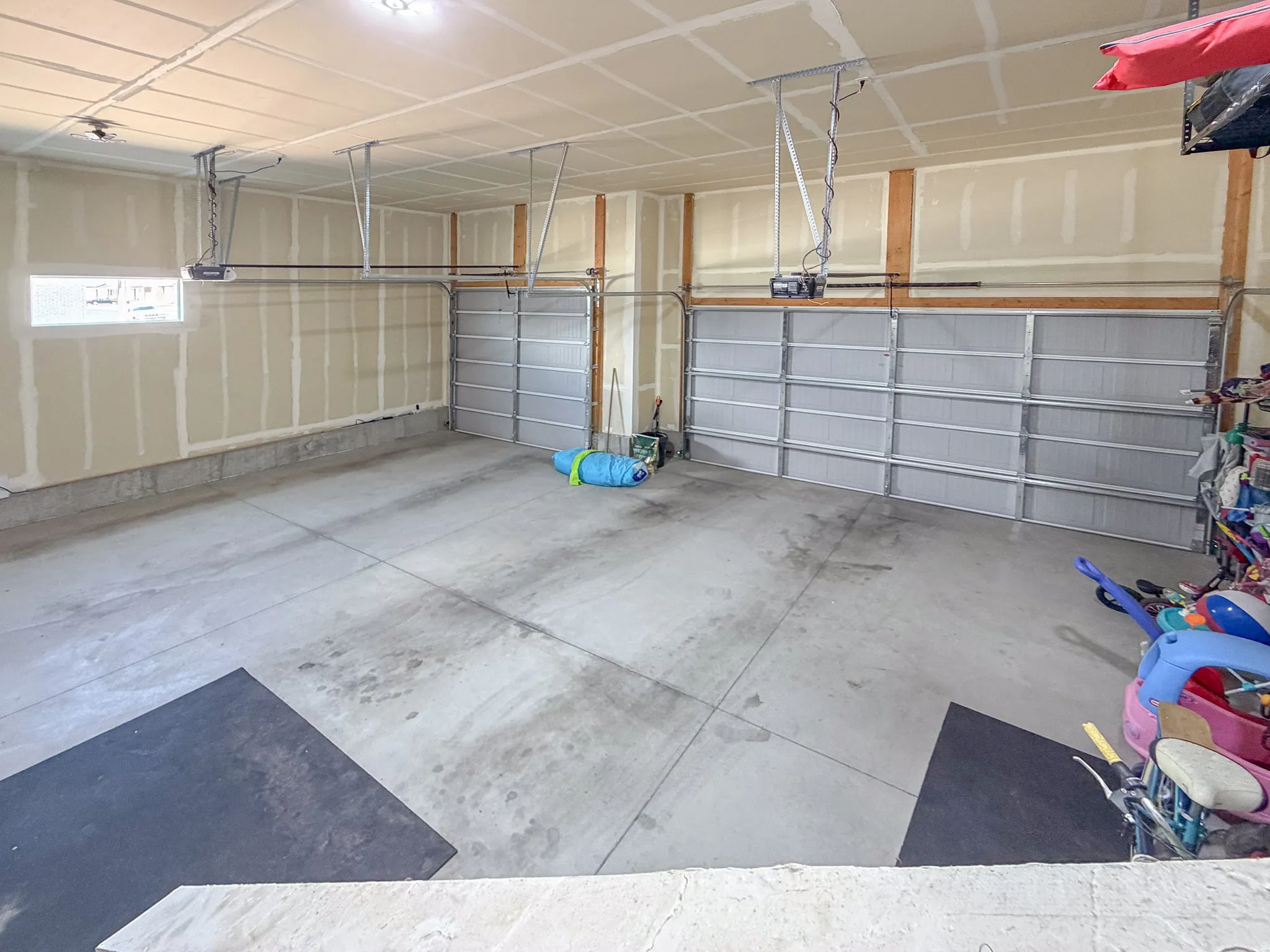 Spacious garage featuring a concrete floor, two overhead garage doors, and a single window