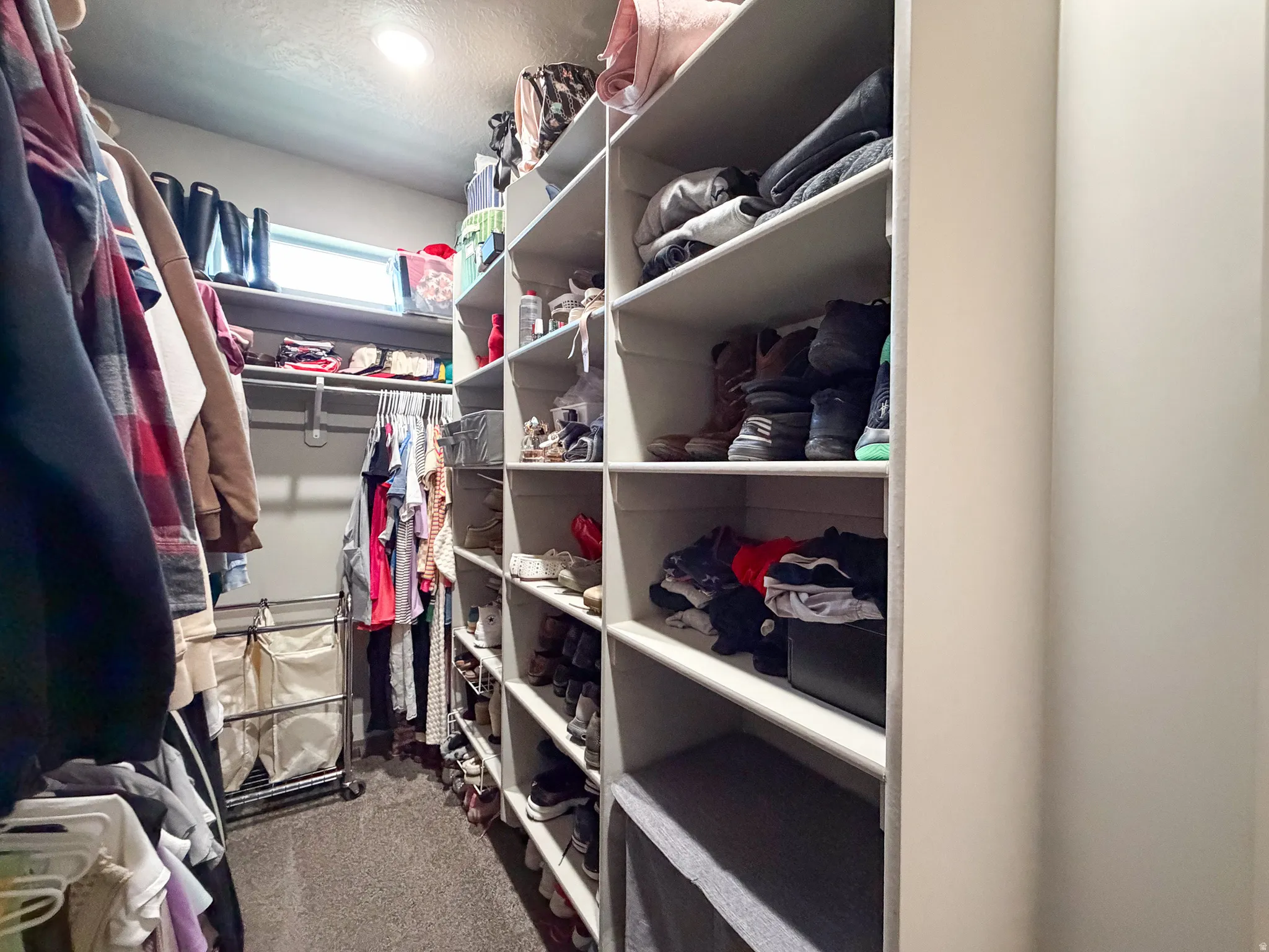 Walk-in closet featuring built-in shelving, multiple hanging rods, and an overhead light fixture