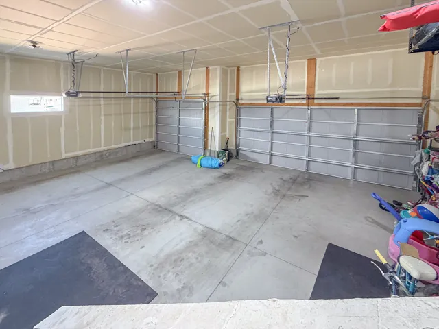 Spacious garage featuring a concrete floor, two overhead garage doors, and a single window
