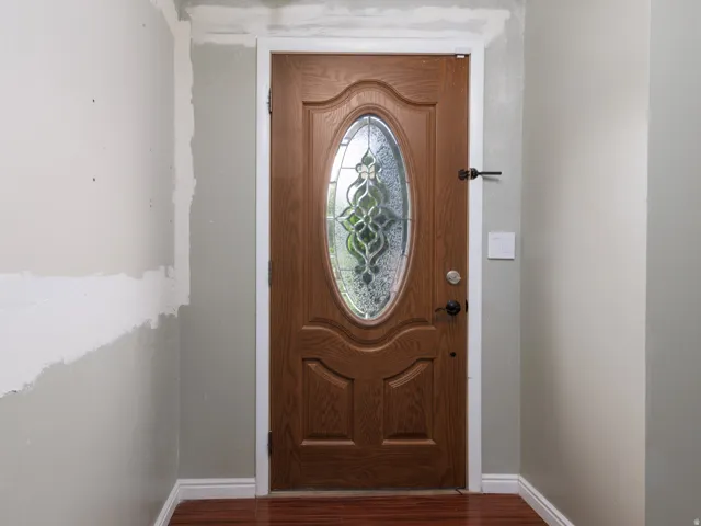 Wood-finish entry door with an oval stained-glass insert, accented by matte black hardware
