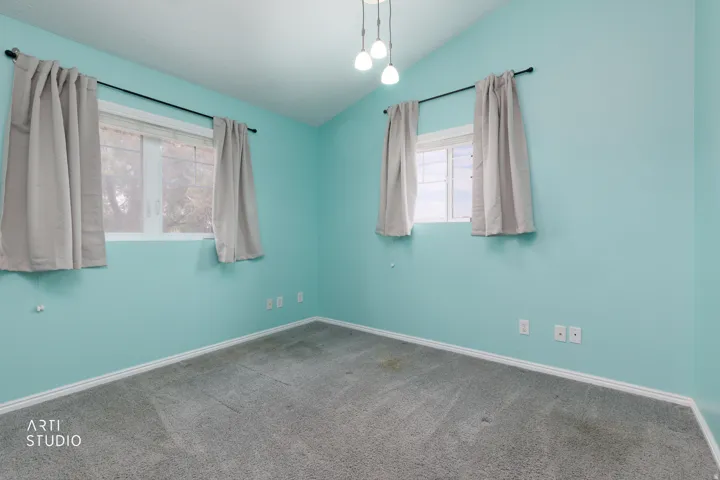 Room featuring two windows with curtain rods, light blue wall paint, gray carpeting, white baseboards, and a contemporary ceiling light fixture