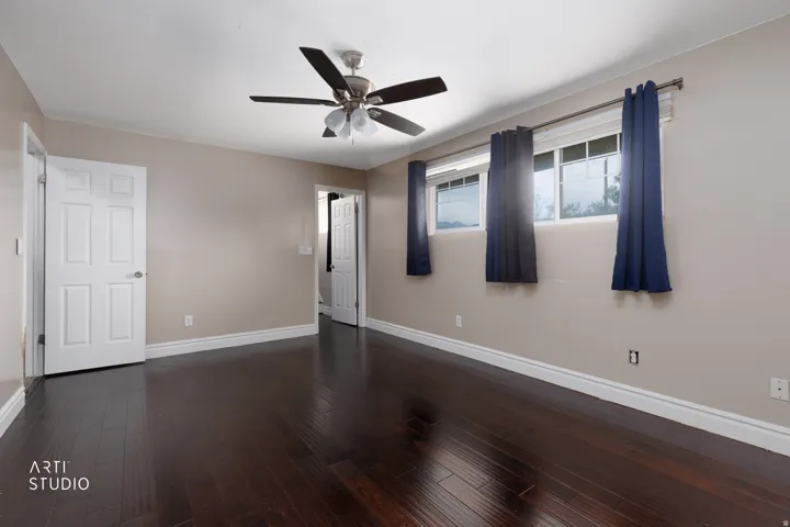 Spacious room featuring wood-finish flooring, light-toned wall paint, and multiple windows