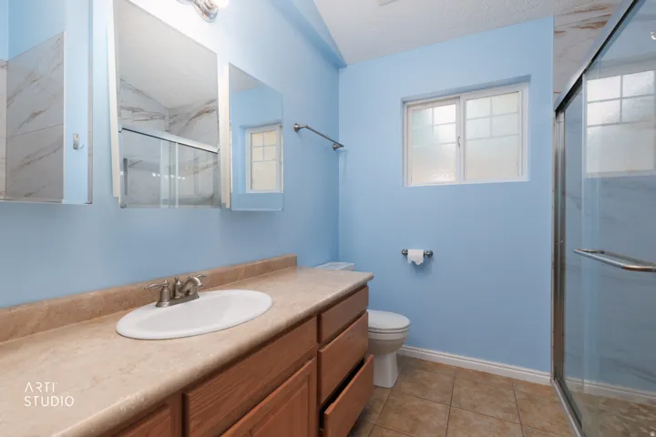 Bathroom featuring a vanity with a laminate countertop, an undermount sink, and wood cabinetry