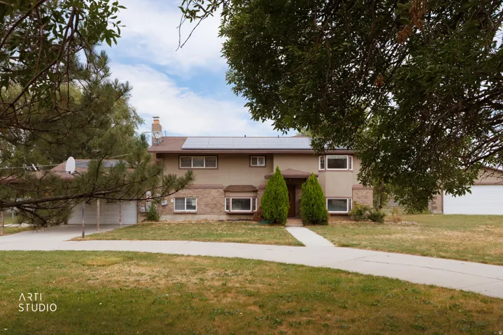 Exterior facade featuring solar panels, multiple bay windows, and a combination of stucco and brick finishes
