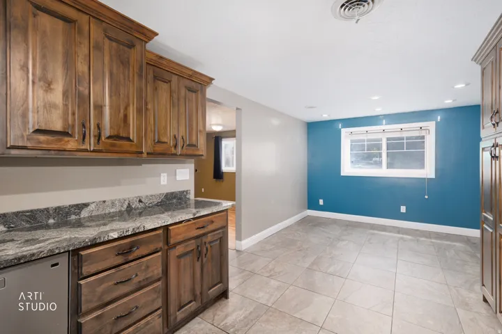Kitchen area featuring wood cabinetry with dark hardware and a mottled gray countertop