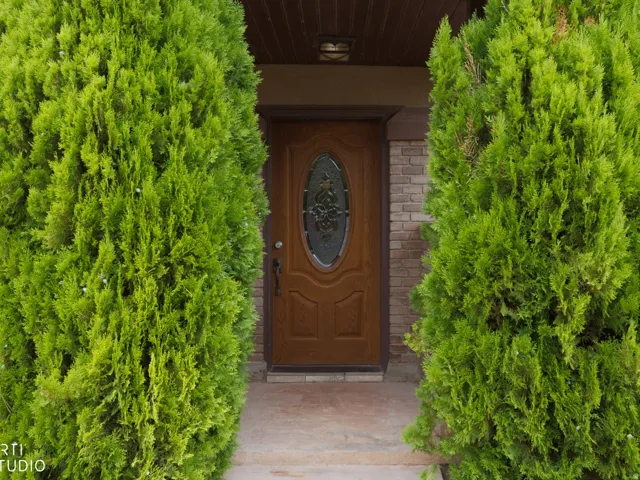 Entryway featuring a wood-panel door with an oval-shaped leaded glass insert, brick veneer siding, and a concrete stoop