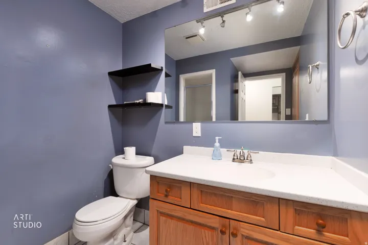 Bathroom featuring a light wood-finish vanity with a white countertop, an integrated sink, and track lighting above a large mirror