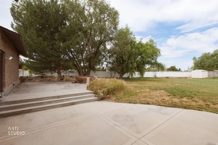 Expansive concrete patio area with multi-level steps, leading to a substantial lawn