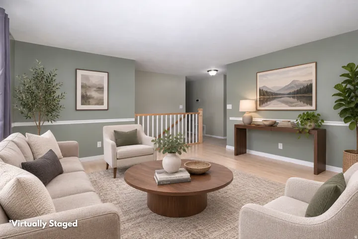 Inviting living area featuring light wood-finish flooring, a neutral area rug, and soft green walls with white chair rail molding
