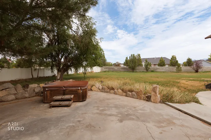 Backyard featuring a concrete patio, a wooden hot tub with matching steps, and stone retaining walls