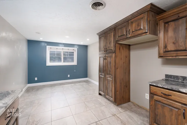 Wood-finish cabinetry and granite-style countertops complement the tile flooring