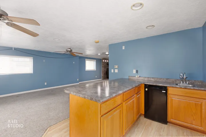 Wet bar featuring wood cabinetry, a built-in beverage refrigerator, and a stainless steel sink with chrome faucet