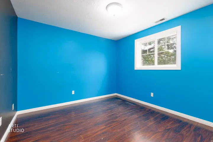 Room featuring a window with white trim, wood-finish flooring, and a flush-mount ceiling light