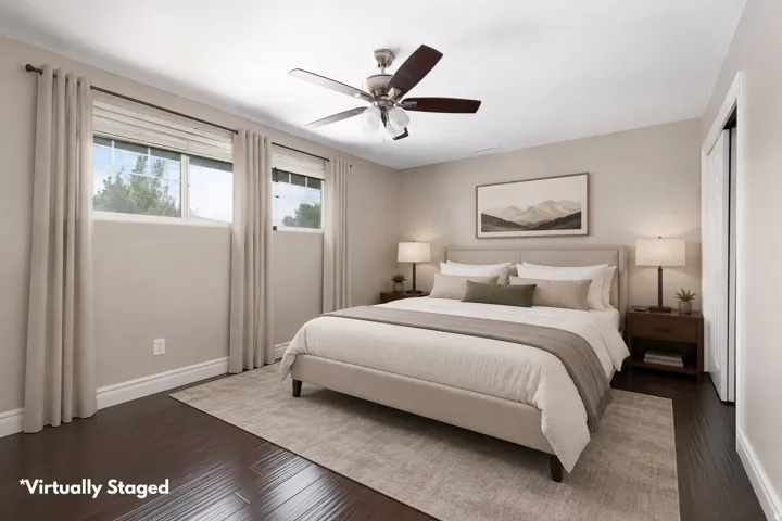 Spacious interior featuring dark wood-finish flooring, light neutral wall tones, a ceiling fan with integrated lighting, and multiple windows with blinds and curtain rods