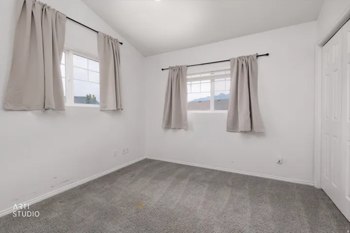 Room featuring a vaulted ceiling, gray carpet flooring, and white baseboards