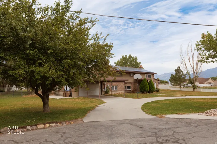 Brick exterior residence featuring an attached two-car garage, established front yard landscaping, paved driveway, and mountain backdrop