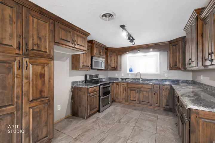 Kitchen featuring extensive wood cabinetry, dark-toned countertops, stainless steel appliances, and tiled flooring