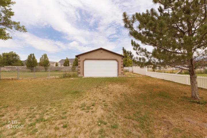 Detached garage featuring stucco exterior, arched trim detailing, and a white overhead door