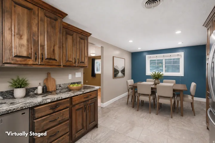 Kitchen and dining area featuring rich wood cabinetry, granite countertops, and a stainless steel dishwasher
