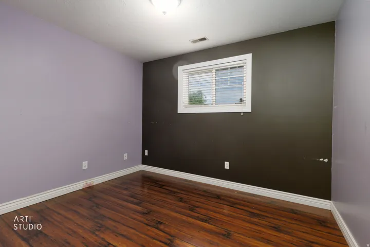 Room featuring wood-finish flooring, a window with horizontal blinds, and a white ceiling light fixture
