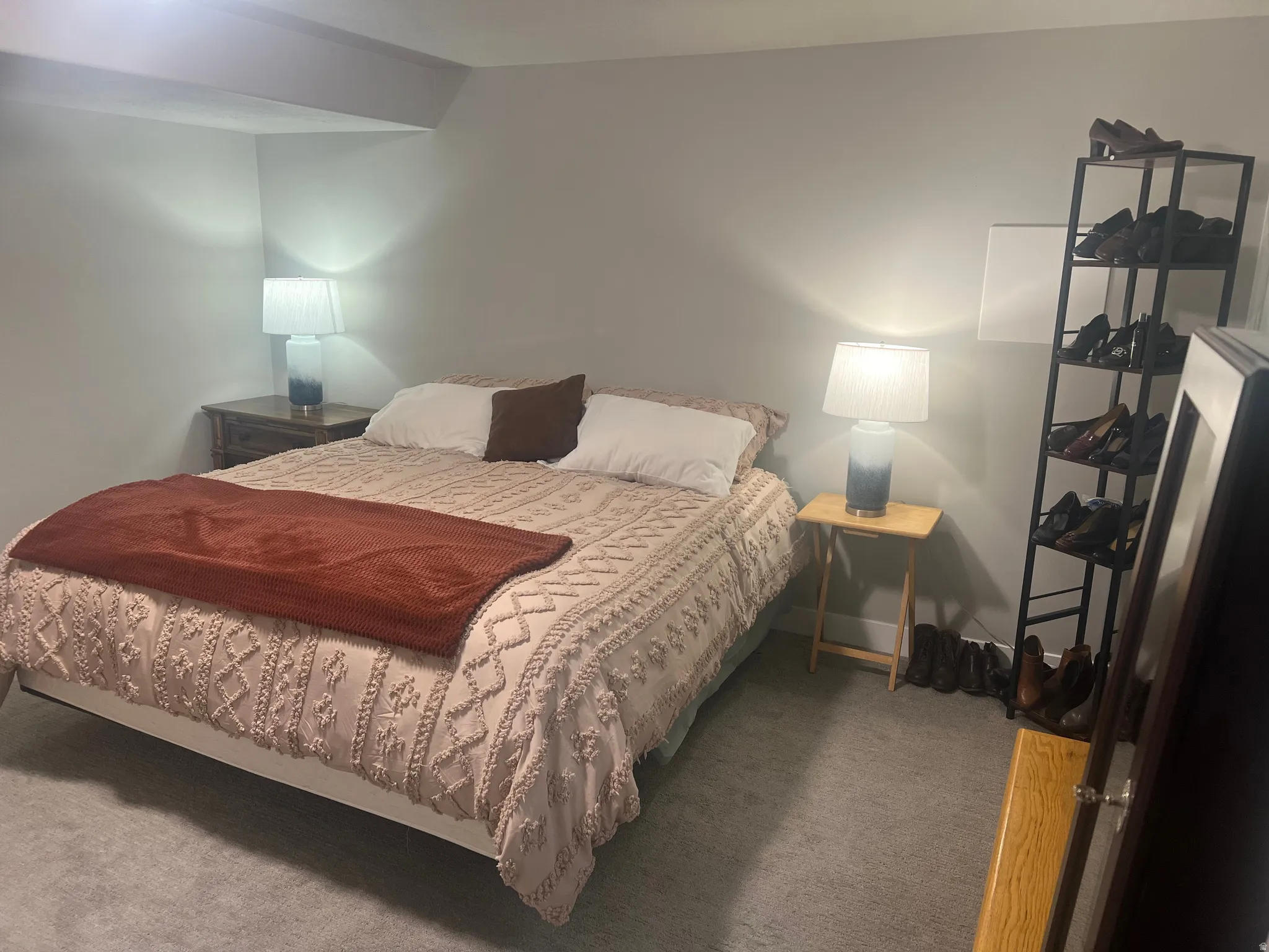 Carpeted room featuring light gray walls, a built-in ceiling beam, and dual bedside tables with lamps