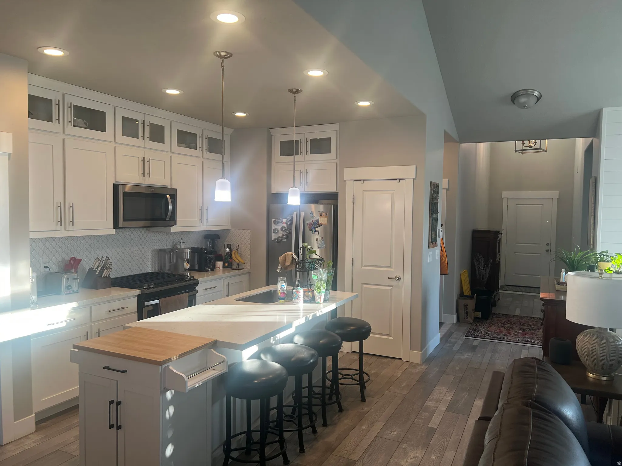 Modern kitchen featuring white shaker cabinetry with frosted glass accents, stainless steel appliances, and a diagonal tile backsplash