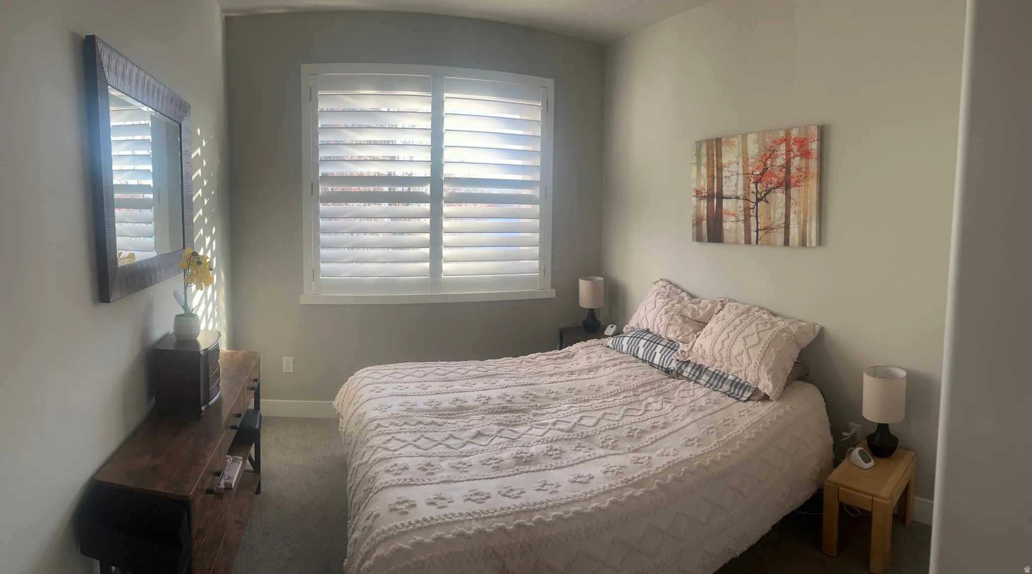 Carpeted room featuring a large window with white plantation shutters, light gray wall paint, and white baseboards