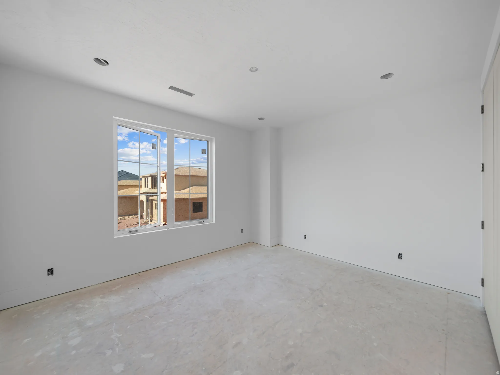 Room featuring a large white-framed window, recessed ceiling lighting, and a white interior door