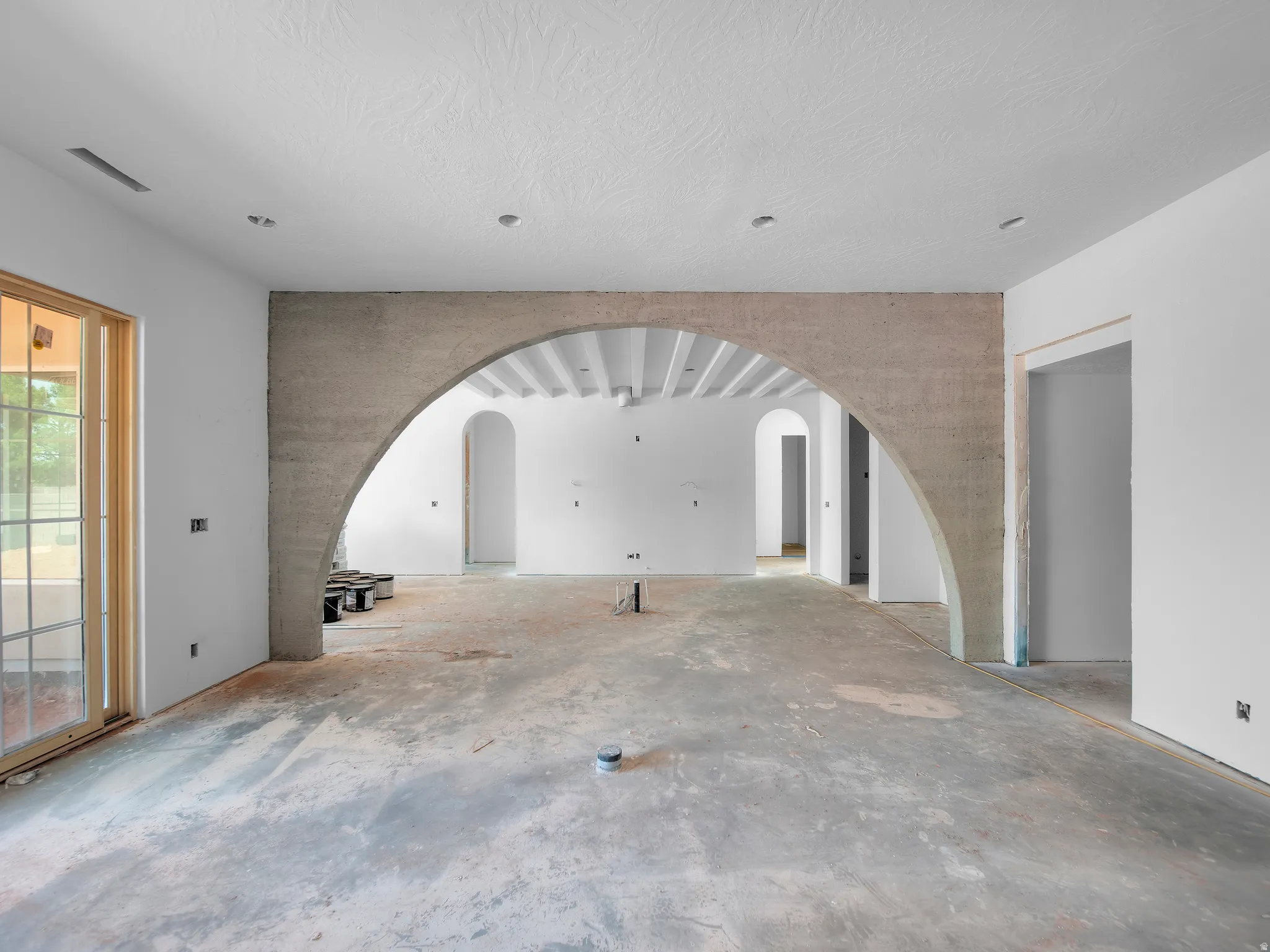 Spacious interior featuring a large arched entryway and a sliding glass door with multiple window panes