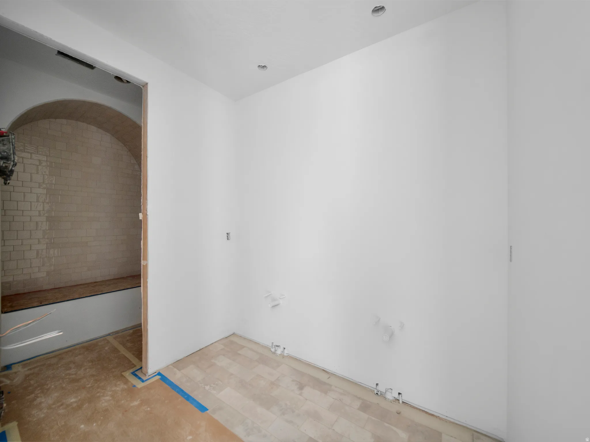 Arched entryway with subway tile wall and integrated bench