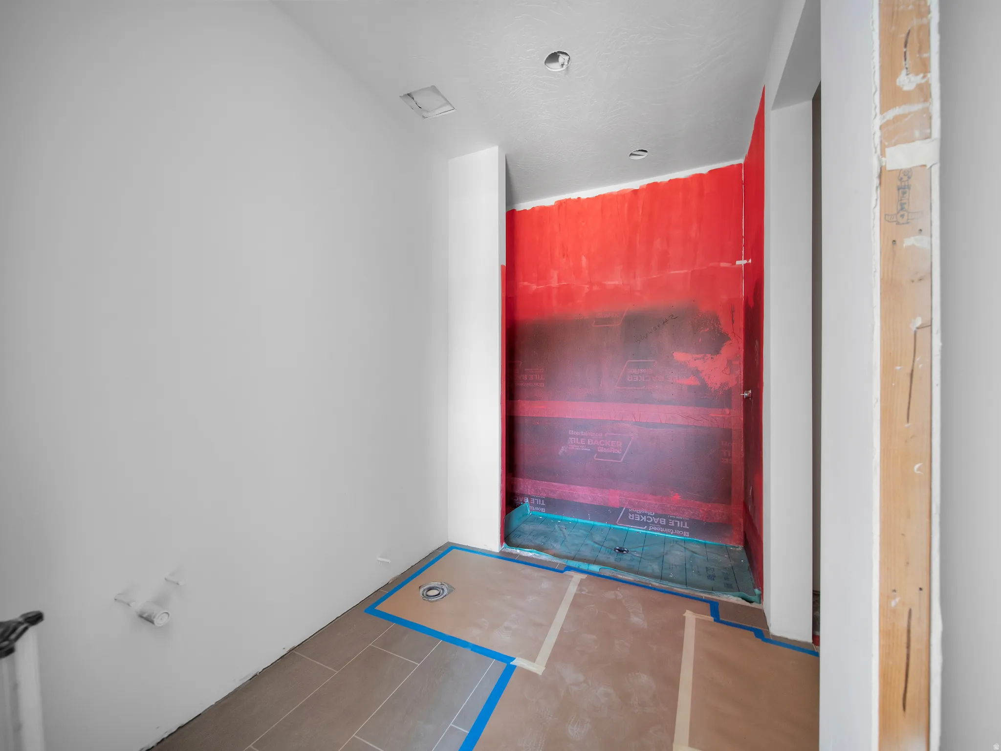 Walk-in shower enclosure featuring waterproofing membrane and integrated shower drain