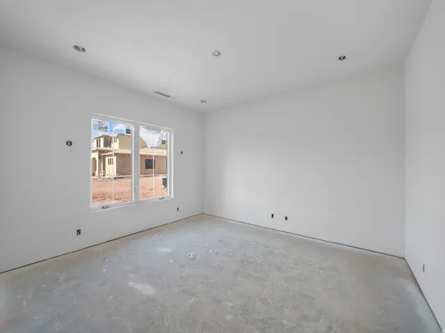 Spacious room featuring a large window, recessed lighting, white walls, a textured ceiling, and an exposed concrete floor