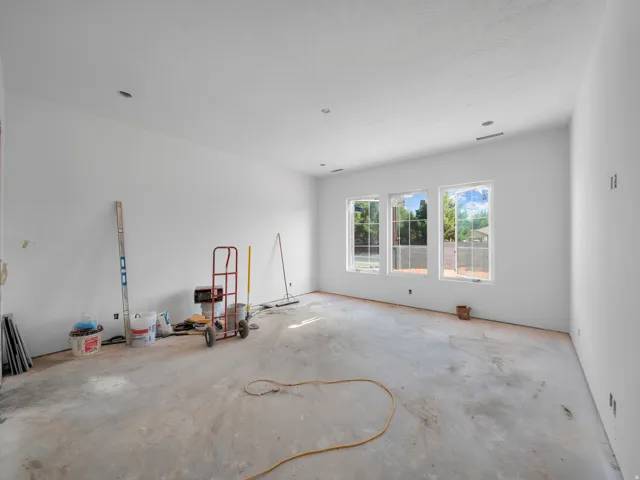 Spacious room featuring three large windows, white walls, and a textured ceiling