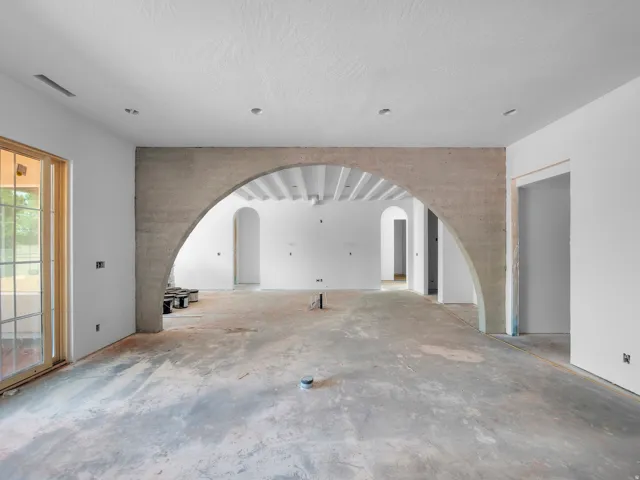 Spacious interior featuring a large arched entryway and a sliding glass door with multiple window panes