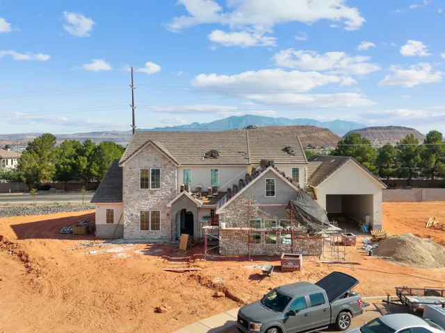 Newly constructed residence featuring a stone and stucco exterior, multi-gabled roofline, and an integrated garage