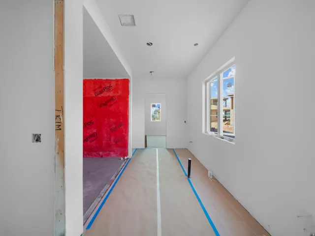 Unfinished interior space featuring white walls, recessed lighting, and a large window providing ample natural light