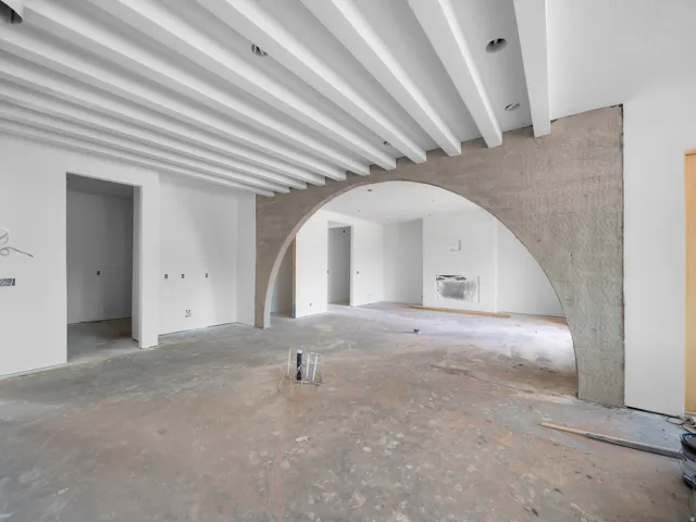 Exposed beam ceiling design with recessed lighting, an architectural archway, and a visible fireplace rough-in
