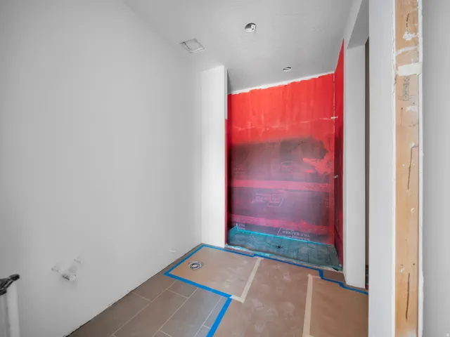 Walk-in shower enclosure featuring waterproofing membrane and integrated shower drain