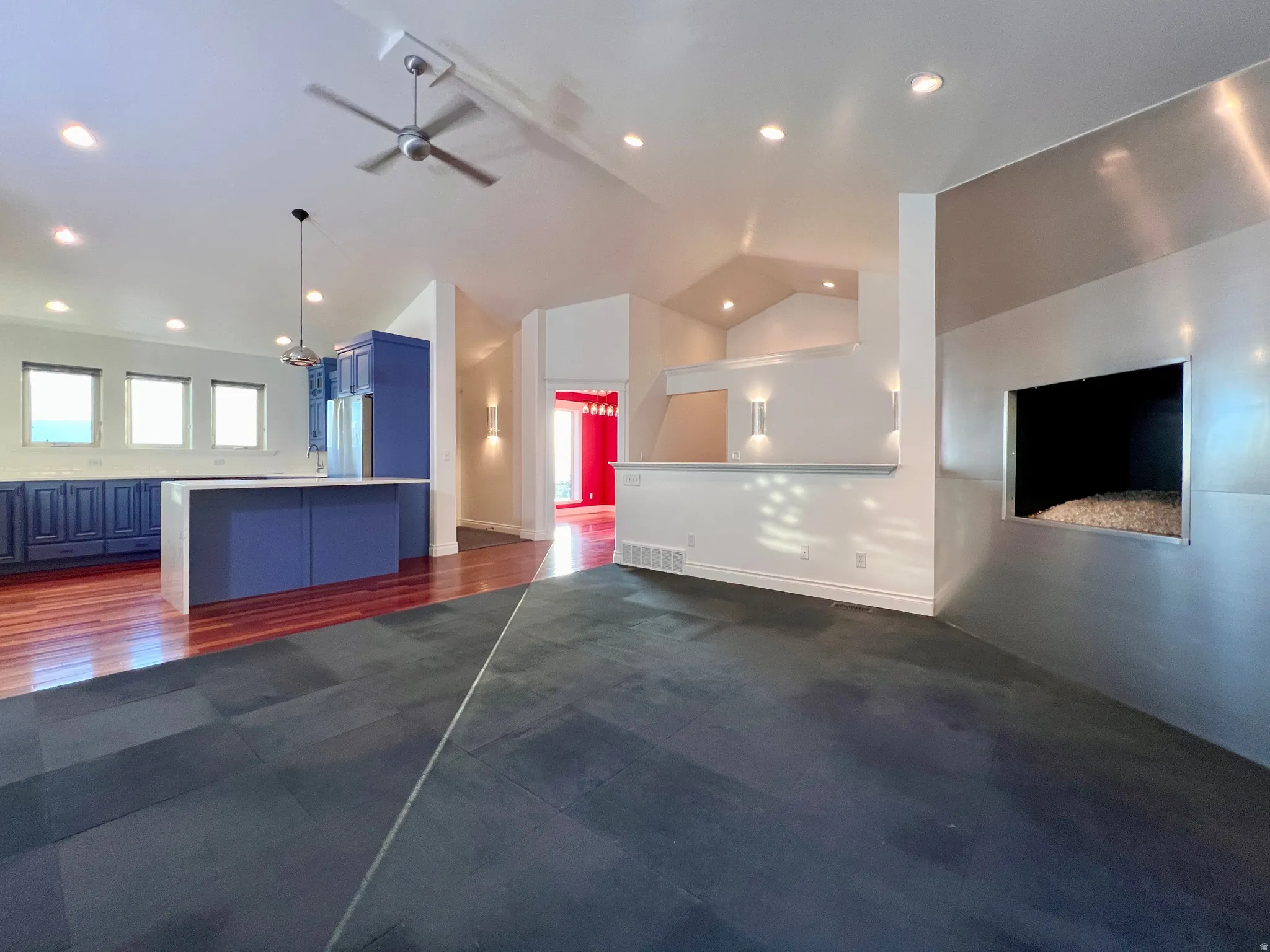 Open-concept living area featuring a modern fireplace with a metallic surround, dark tile flooring, and vaulted ceilings