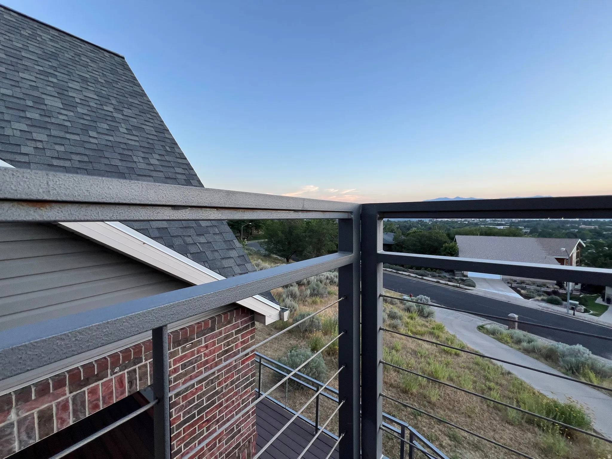 Balcony with contemporary cable railing and composite decking, offering expansive neighborhood views and distant mountains